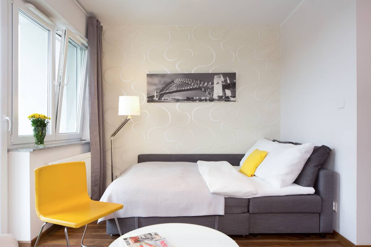 Quarto com cama, cadeira, luminária e parede com uma imagem impressa.