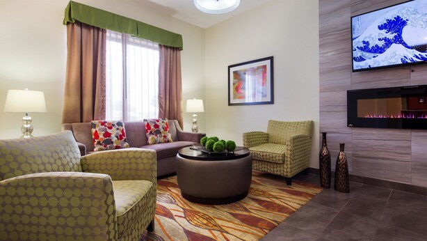 A modern living room with a sofa, armchairs, a coffee table, and a flat-screen TV mounted on the wall. - Best Western Plus Fairview Inn & Suites (Fairview)