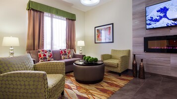 A modern living room with a sofa, armchairs, a coffee table, and a flat-screen TV mounted on the wall.