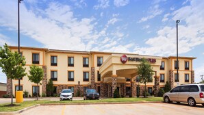 A Best Western Plus hotel with a two-story structure, multiple windows, and a parking lot with two cars. - Best Western Plus Fairview Inn & Suites (Fairview)