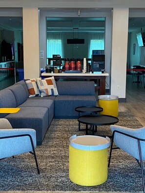 A modern living room with a sectional sofa, two round tables, and a yellow ottoman.