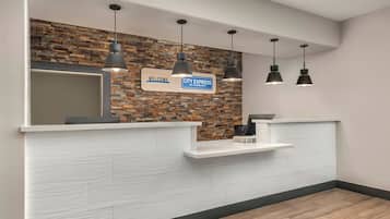 Een receptiebalie met een 'Welcome City Express by Marriott' bord, een spiegel en hanglampen.