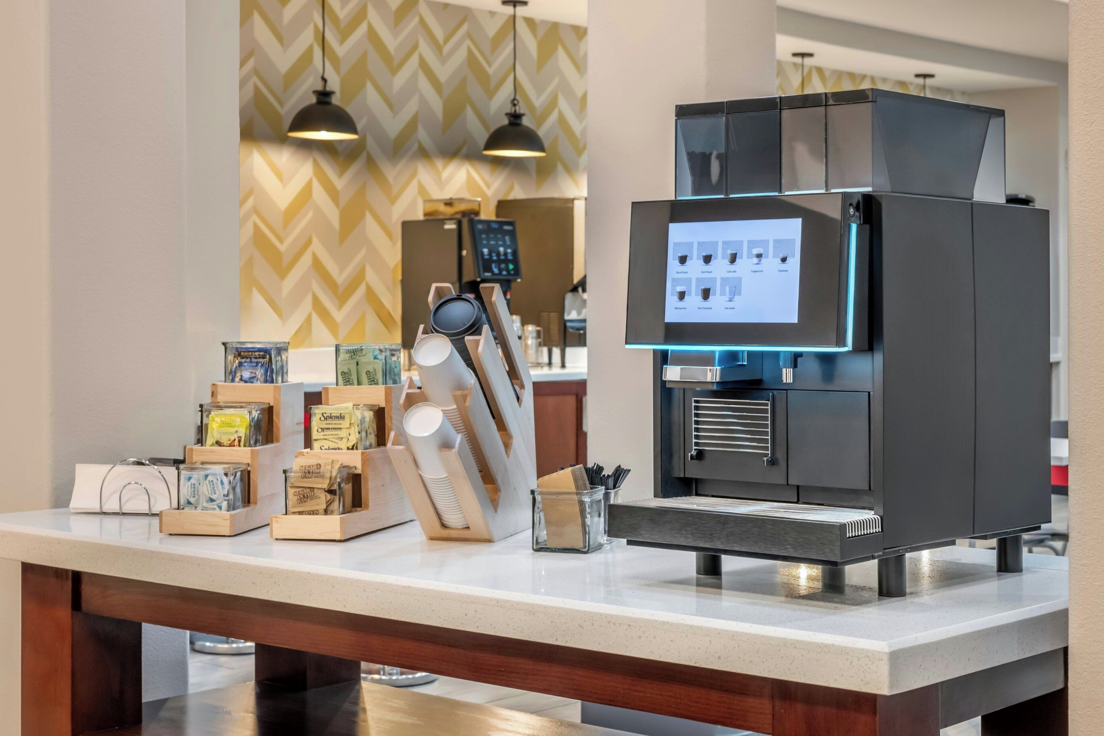 Une machine à café dotée d’un écran numérique et d’un assortiment de capsules de café, le tout placé sur un comptoir.
