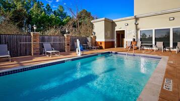 Relax by the pool surrounded by comfortable lounge chairs and a small table.