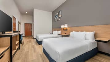 Une chambre d’hôtel avec deux lits, un bureau avec une télévision et un petit coin salon.