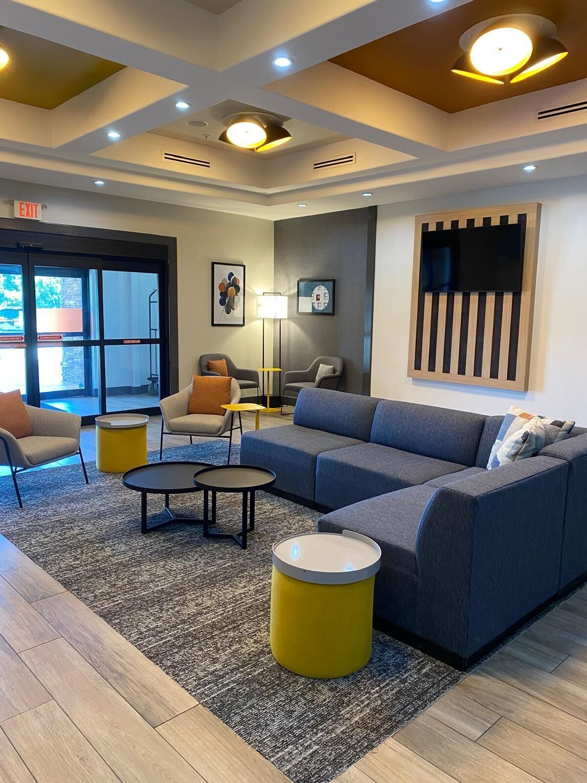 A modern lobby with a sofa, chairs, a coffee table, and a lamp.