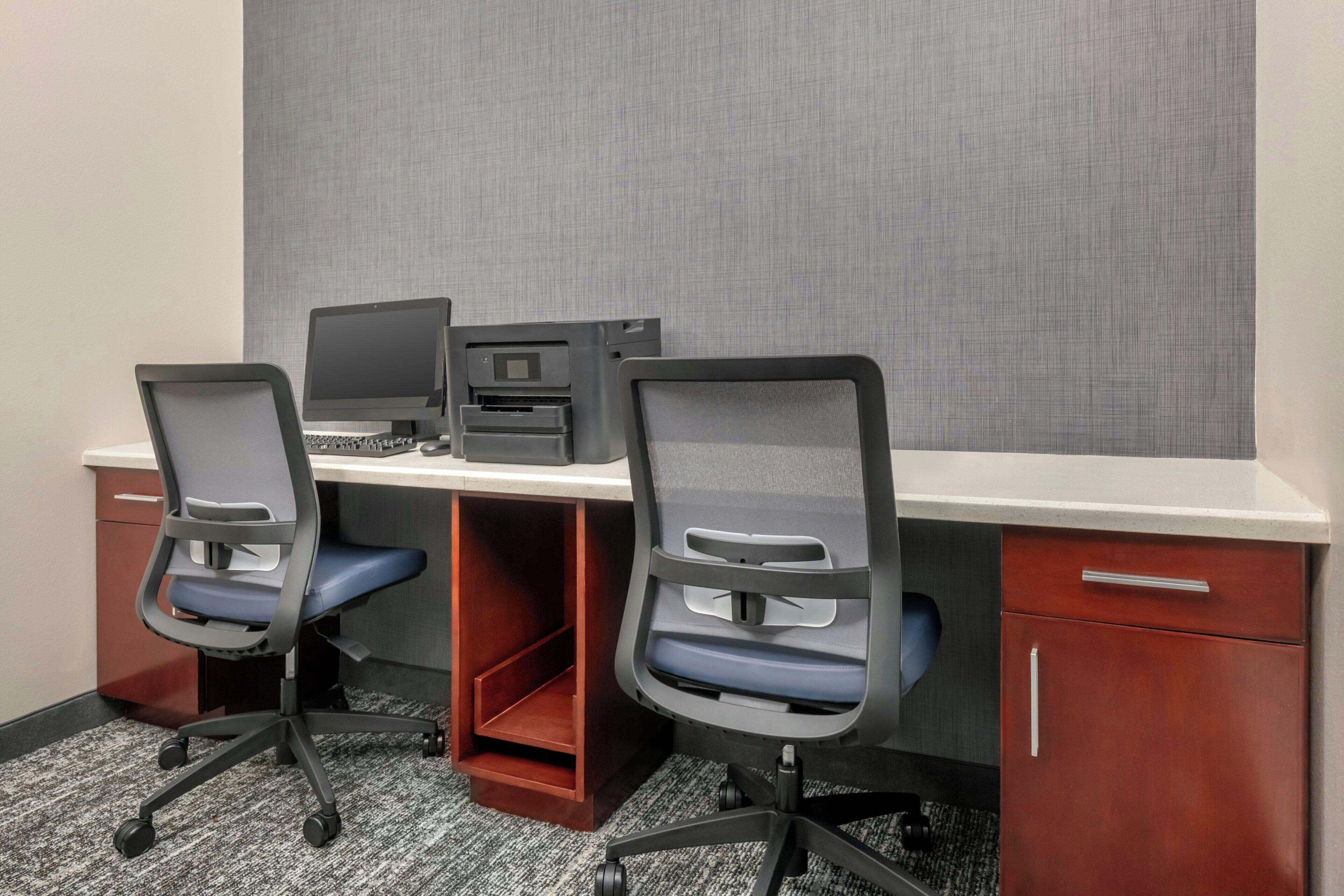 A workspace with two office chairs, a desk, a printer, and a filing cabinet.