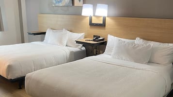 Habitación de hotel con dos camas, una mesita de noche y una obra de arte en la pared.