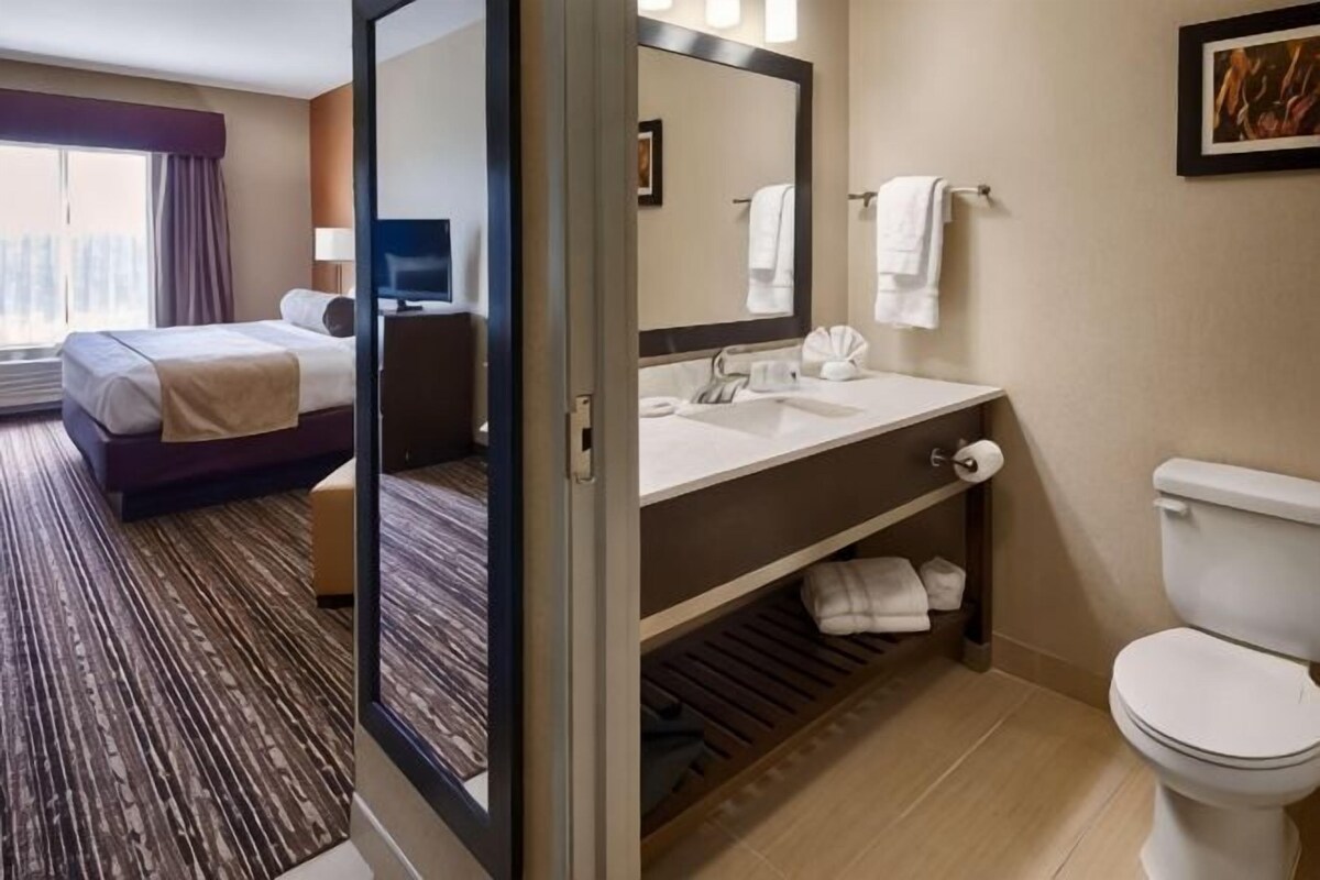 Une chambre d’hôtel avec un lit, une salle de bain comprenant un lavabo et des toilettes, et un grand miroir.