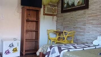 Cozy retreat with a bed, wardrobe, and refrigerator, set against a beautiful floral painting.