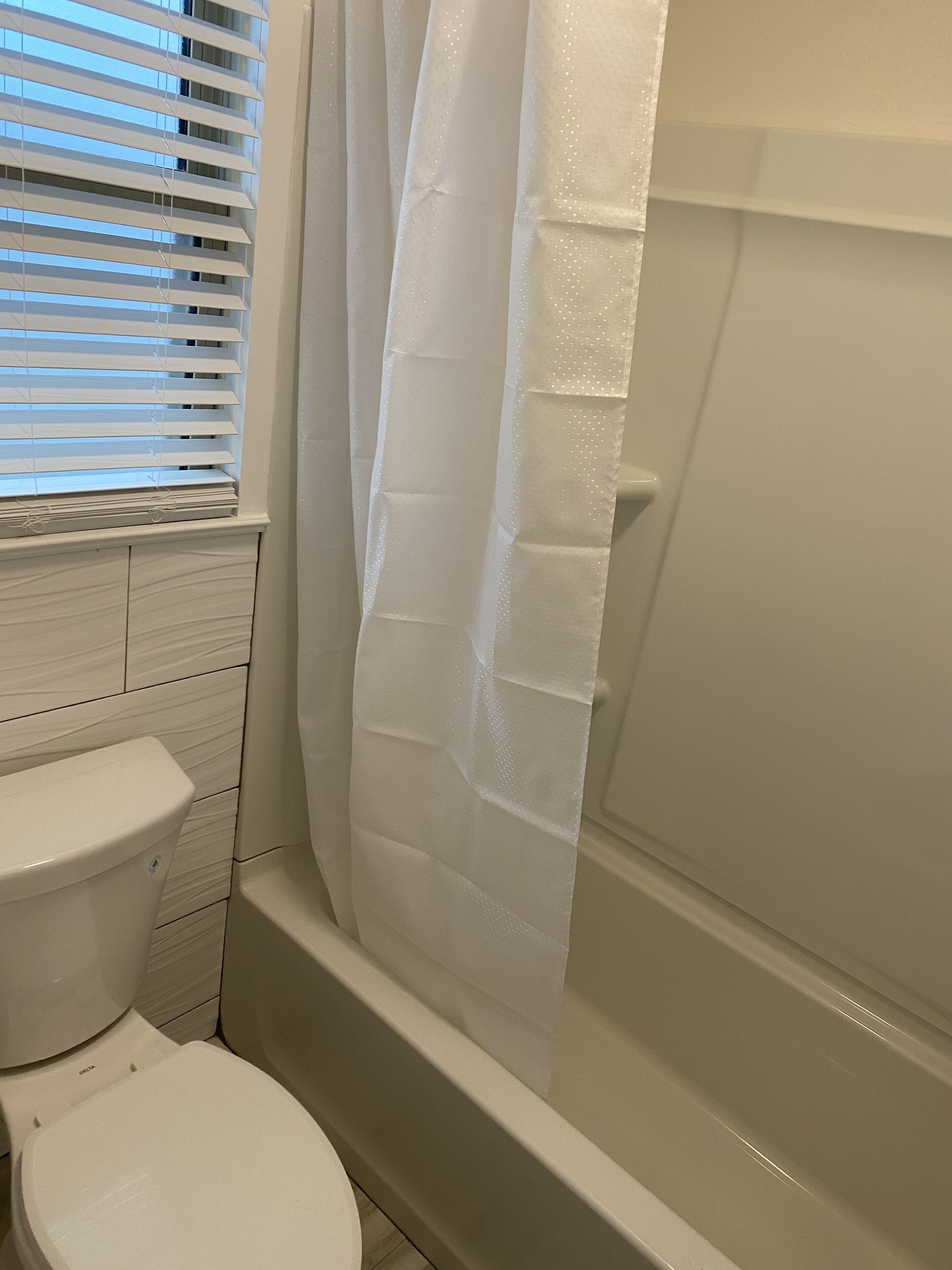 Une salle de bain équipée de toilettes, d’une baignoire et d’un rideau de douche.