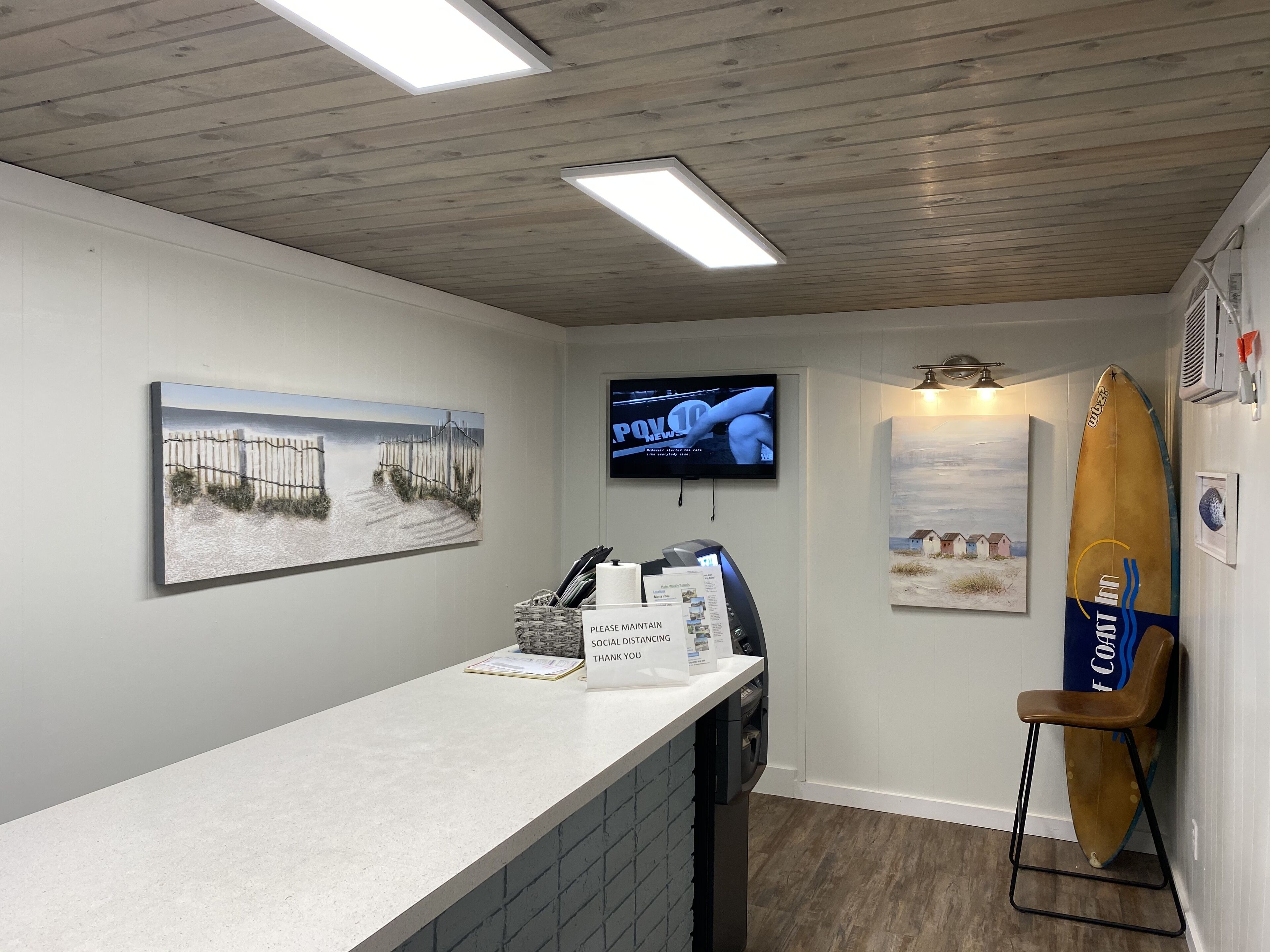 A reception area with a counter, a television, and artwork on the walls.