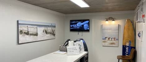 A reception area with a counter, a television, and artwork on the walls.