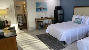 Una camera d'albergo con un letto, un comodino, una lampada e un quadro appeso al muro.