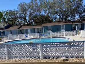 A swimming pool with a white lattice fence, surrounded by pebbles.