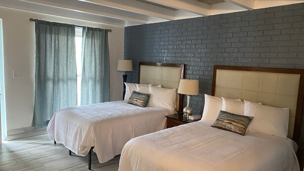 Ein Hotelzimmer mit zwei Betten, einer Ziegelwand und einer Holzbalkendecke.