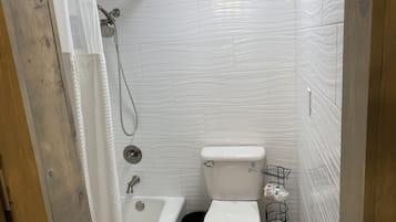 Ein kleines Badezimmer mit einer weißen Badewanne, Toilette und Dusche.