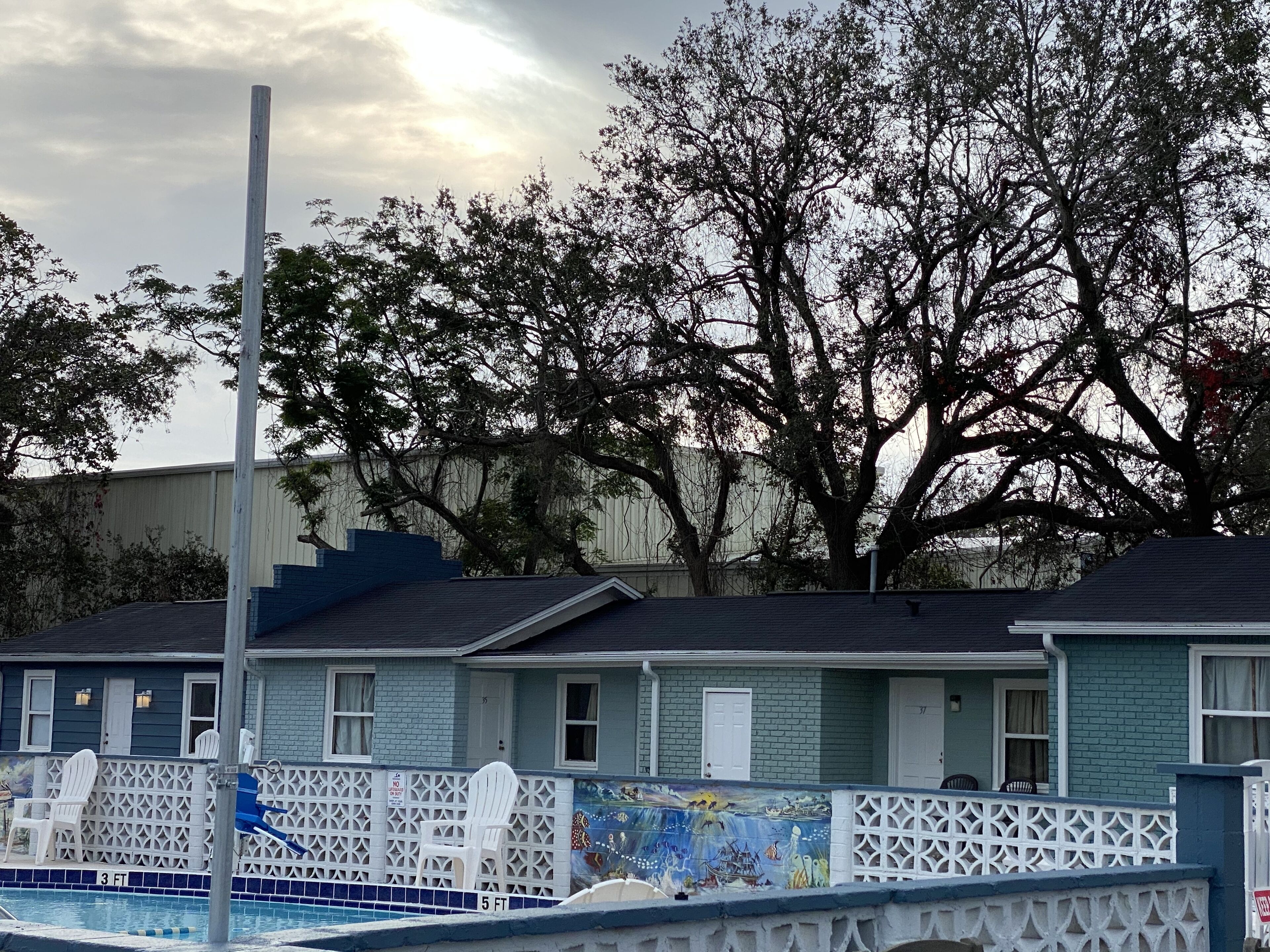 Una hilera de edificios pequeños de una planta, con una piscina al frente.