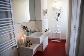 A modern bathroom with a white sink, mirror, and shelves with toiletries. - Le Dimore dell'Acqua (Matera)