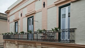 A building facade with three windows, a balcony with a wrought iron railing, and a small table with potted plants. - Le Dimore dell'Acqua (Matera)