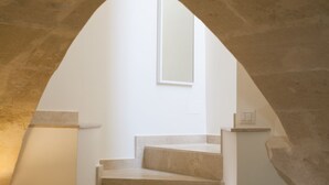 A stone archway leading to a staircase with a white wall and a window above it. - Le Dimore dell'Acqua (Matera)