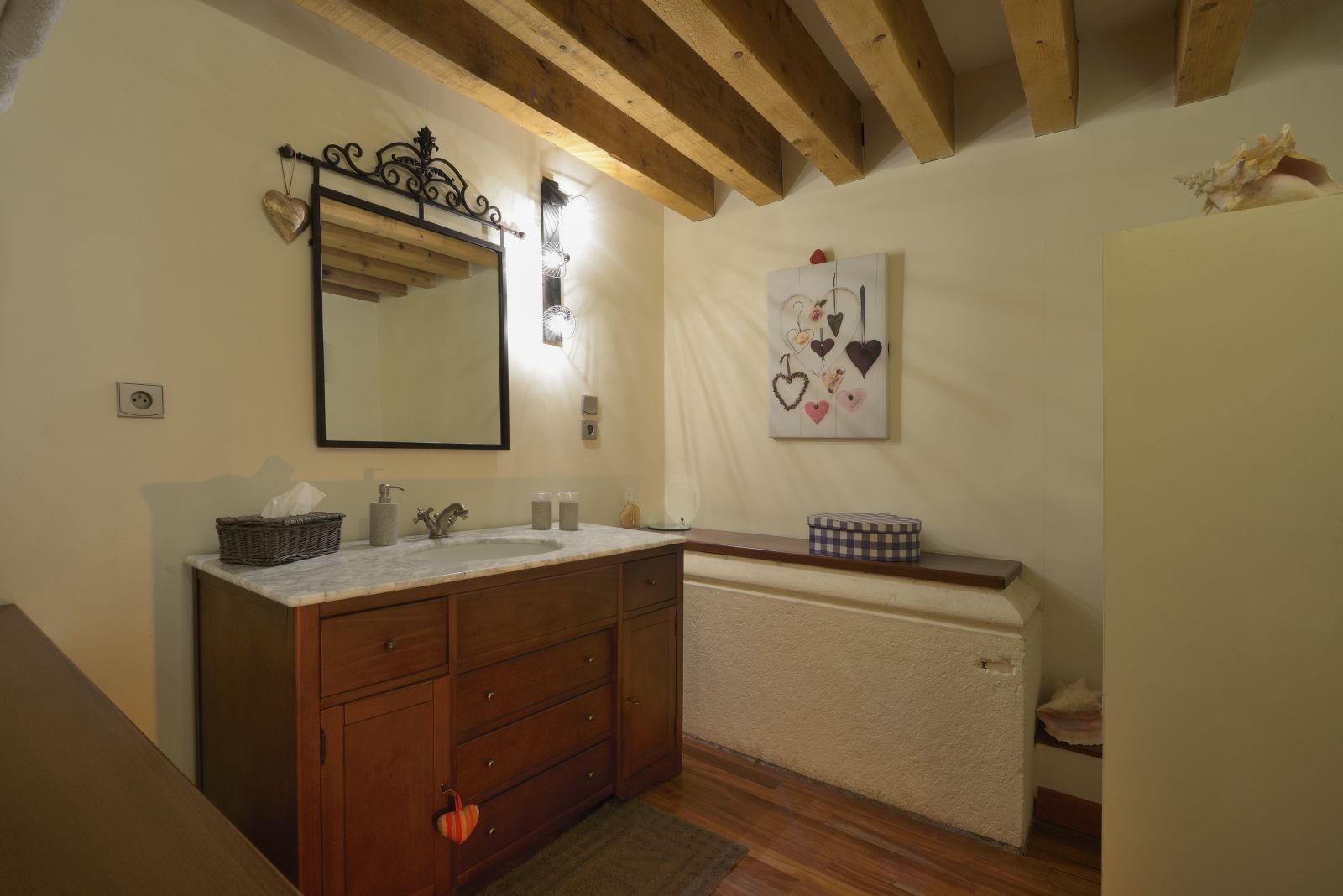 Ein Badezimmer mit einem Holzkosmetikschrank, einem großen Spiegel und einer Wandleuchte.