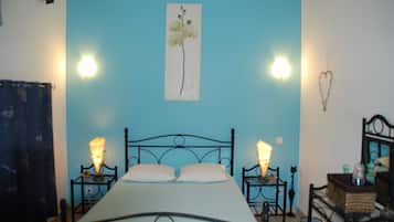 Een slaapkamer met een bed, twee nachtkastjes, een wandlamp en een hartvormige decoratie.