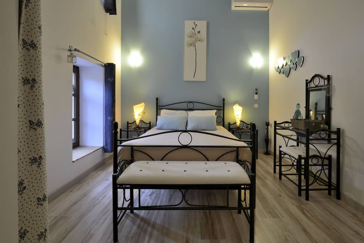Une chambre à coucher comprenant un lit, des tables de chevet, un banc, une commode et un miroir.