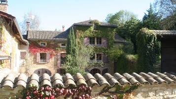 A stone building with a tiled roof, ivy-covered walls, and arched windows.