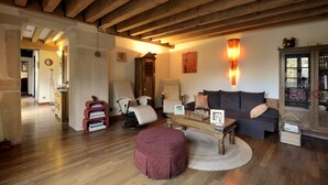 Un salón acogedor con vigas de madera, un sofá, sillones, una mesa de centro y una estantería.