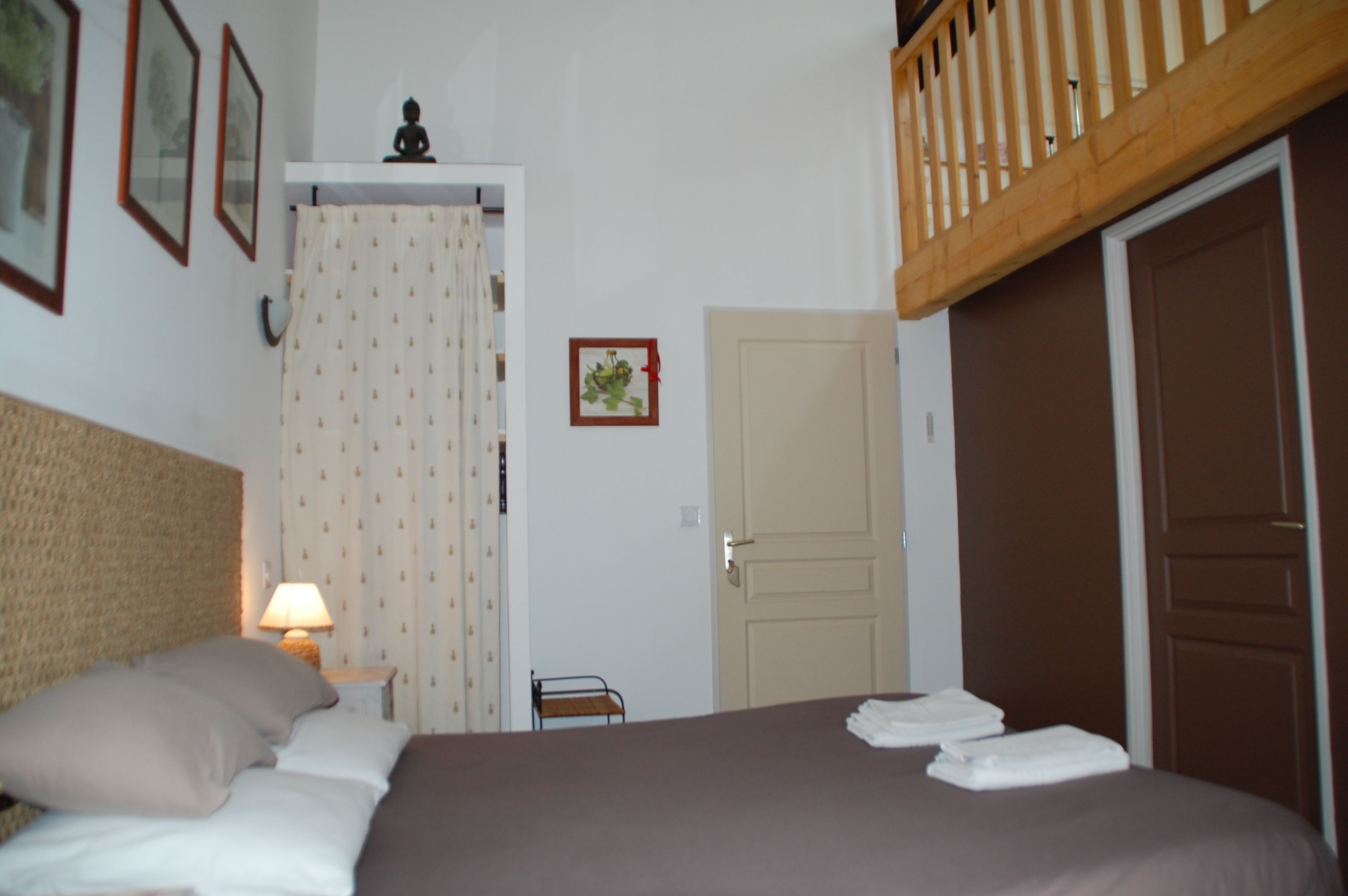 Une chambre à coucher avec un lit, une table de chevet avec une lampe, une porte et une petite chaise.