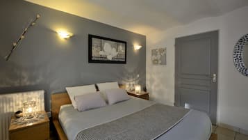 A bedroom with a large bed, two bedside tables, a wall-mounted light, and a door.