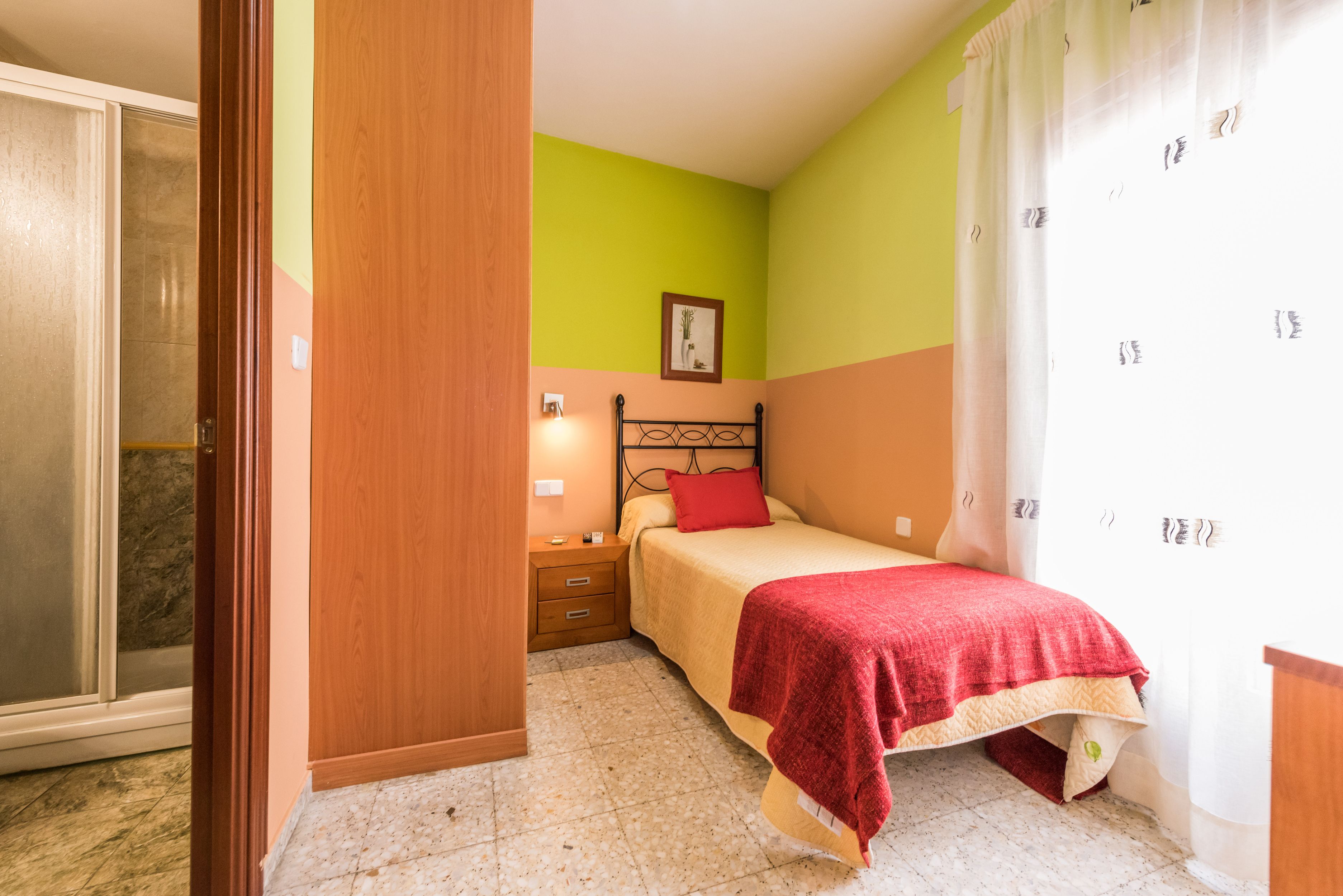 Quarto com cama, mesa de cabeceira, guarda-roupa de madeira e um quadro na parede.