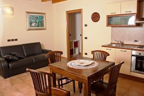 A compact living space with a dining area, a kitchenette, and a sofa. - Agriturismo Radamez (Monzambano)