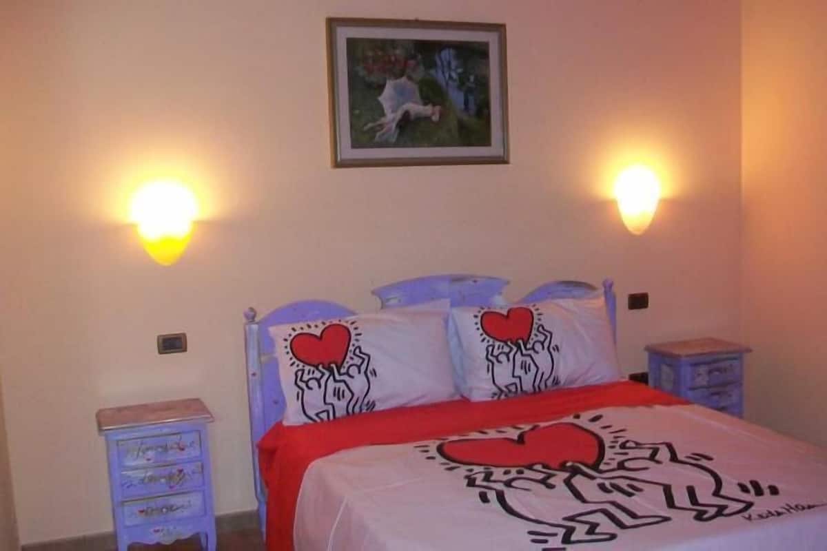 Een slaapkamer met een bed, twee nachtkastjes en een aan de muur hangend schilderij.