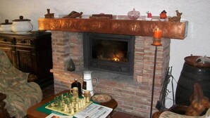 A cozy living room with a brick fireplace, a chessboard, and various decorative items.