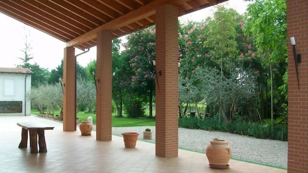 An outdoor patio area with a pergola, brick columns, and terracotta planters.