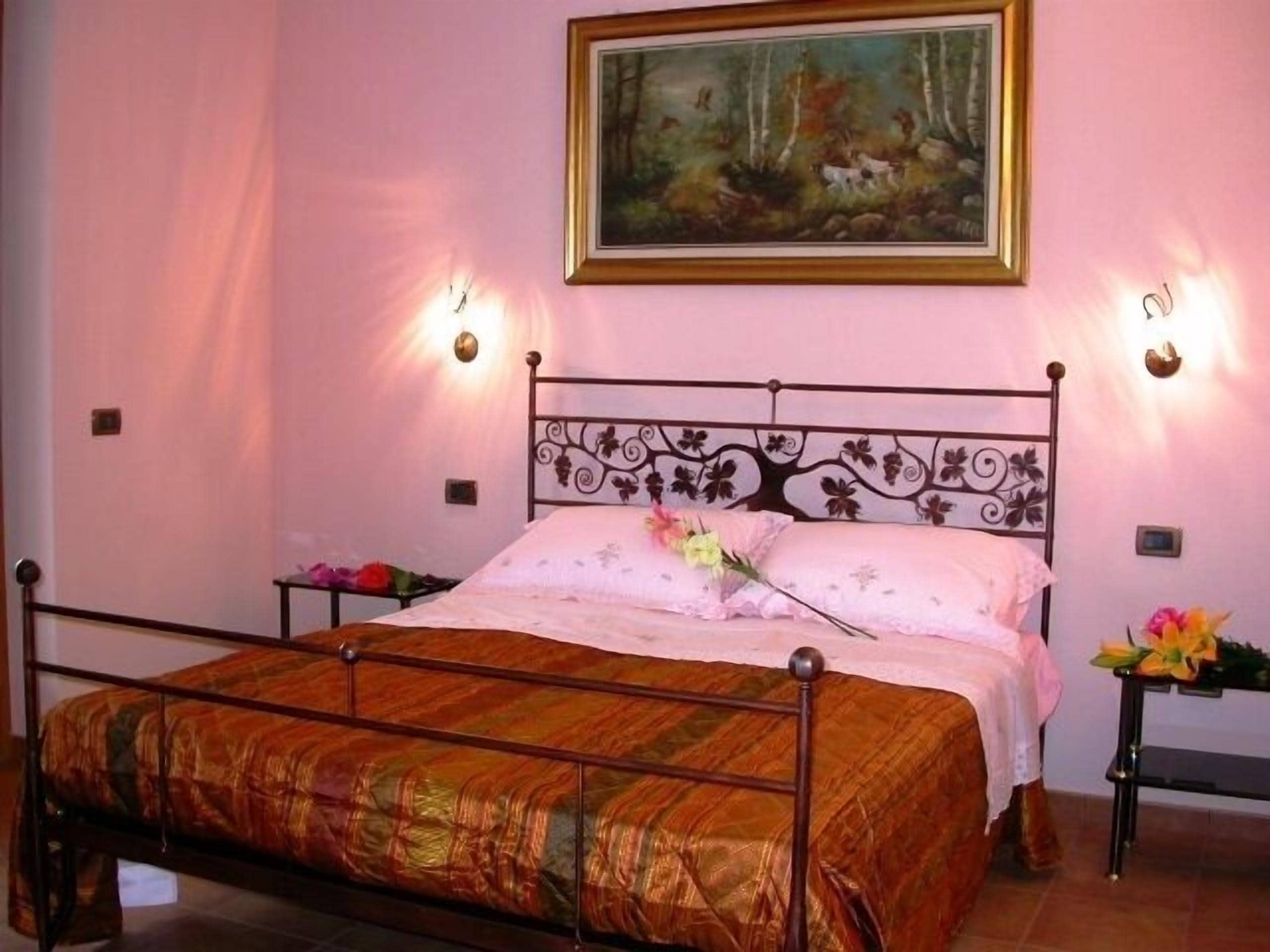 Une chambre à coucher avec un lit, un tableau au mur et deux lampes fixées au mur.