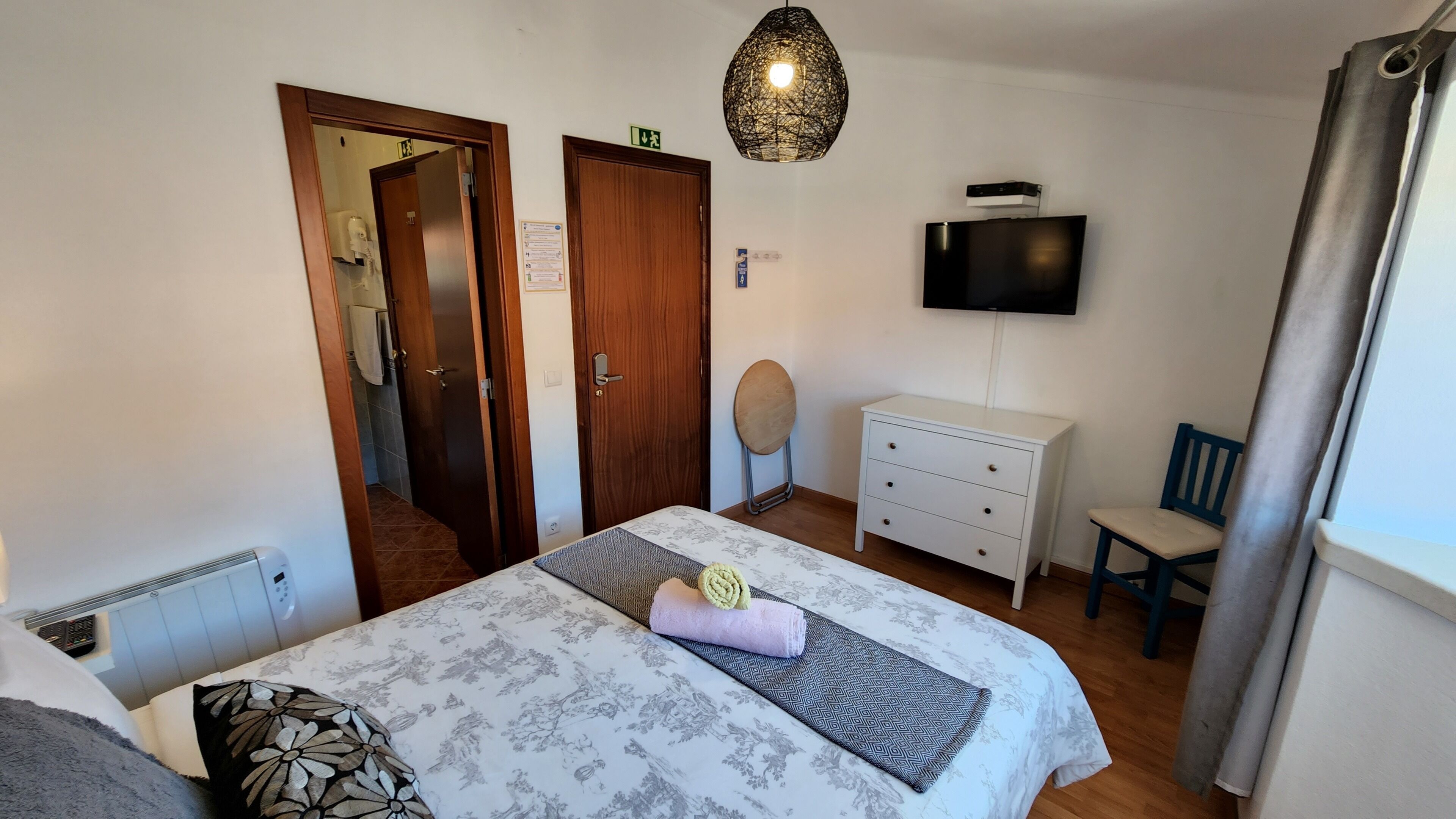 Un dormitorio con cama, cómoda, televisor y silla.
