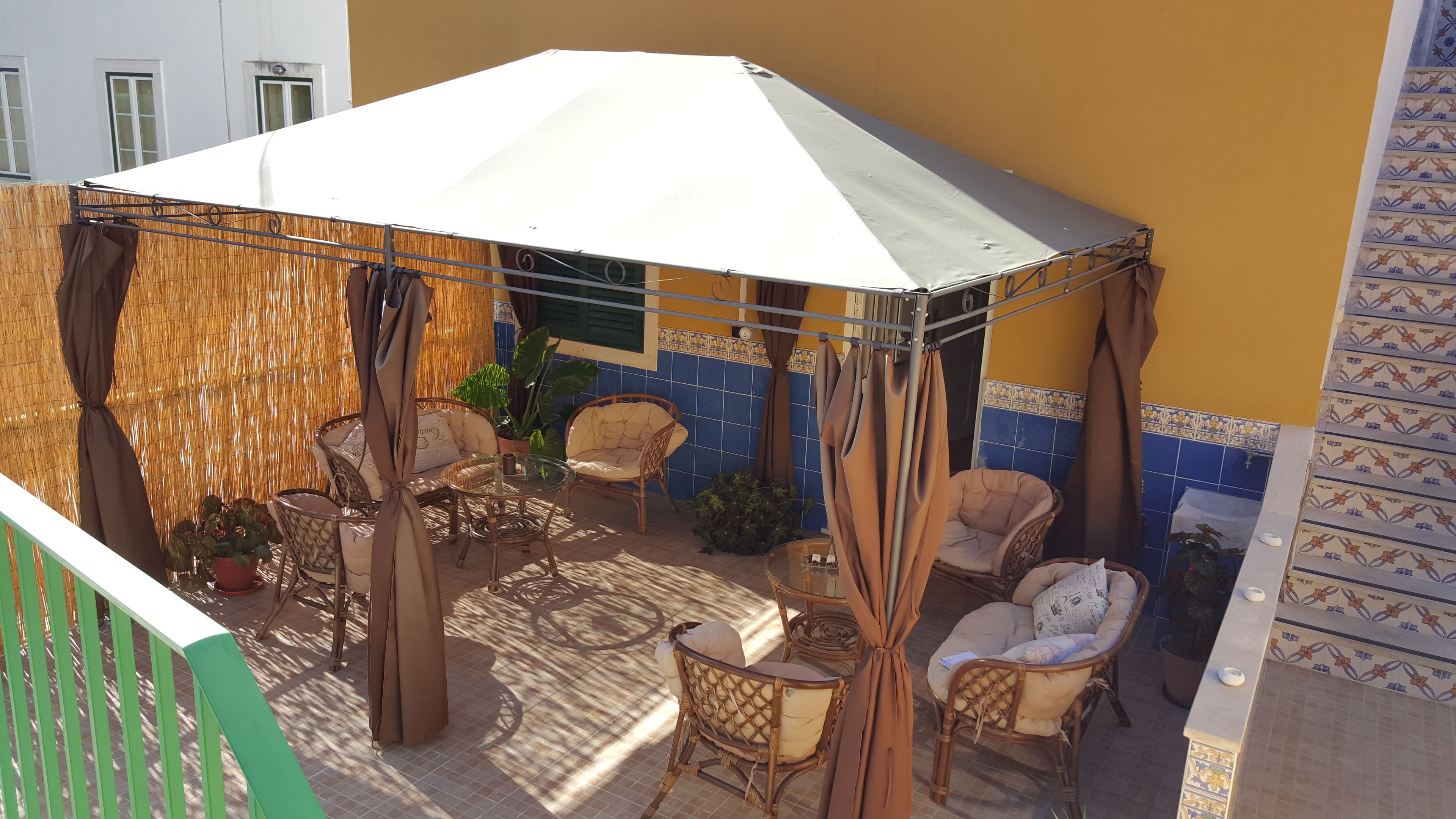 A covered outdoor seating area with wicker furniture and a white canopy.