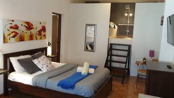A bedroom with a bed, bedside table, lamp, and a painting on the wall.