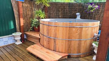 A wooden hot tub with steps and a pergola overhead.
