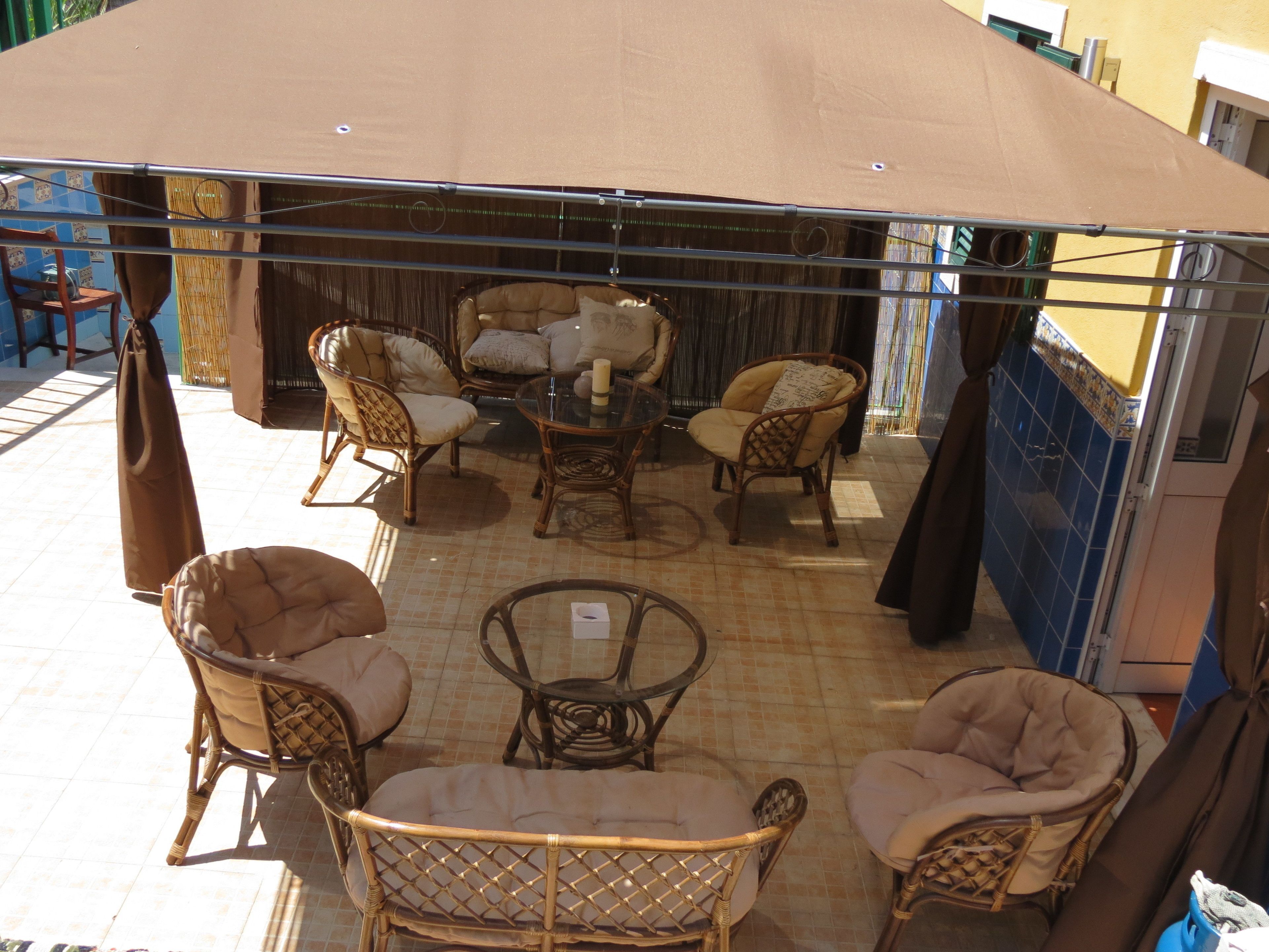 An outdoor seating area with wicker furniture and a covered section.