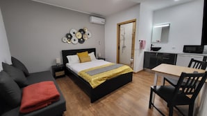 A hotel room with a bed, a desk, a chair, a sofa, and a kitchenette. - Guesthouse of Alcobaça (Alcobaça)