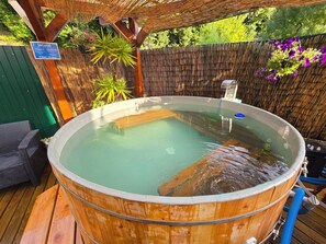 A wooden hot tub with a bamboo backdrop, surrounded by greenery and a sign indicating operating hours. - Guesthouse of Alcobaça (Alcobaça)