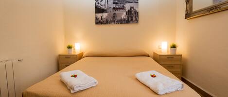 A hotel room with a bed, two bedside tables, a wall-mounted picture, and a mirror.