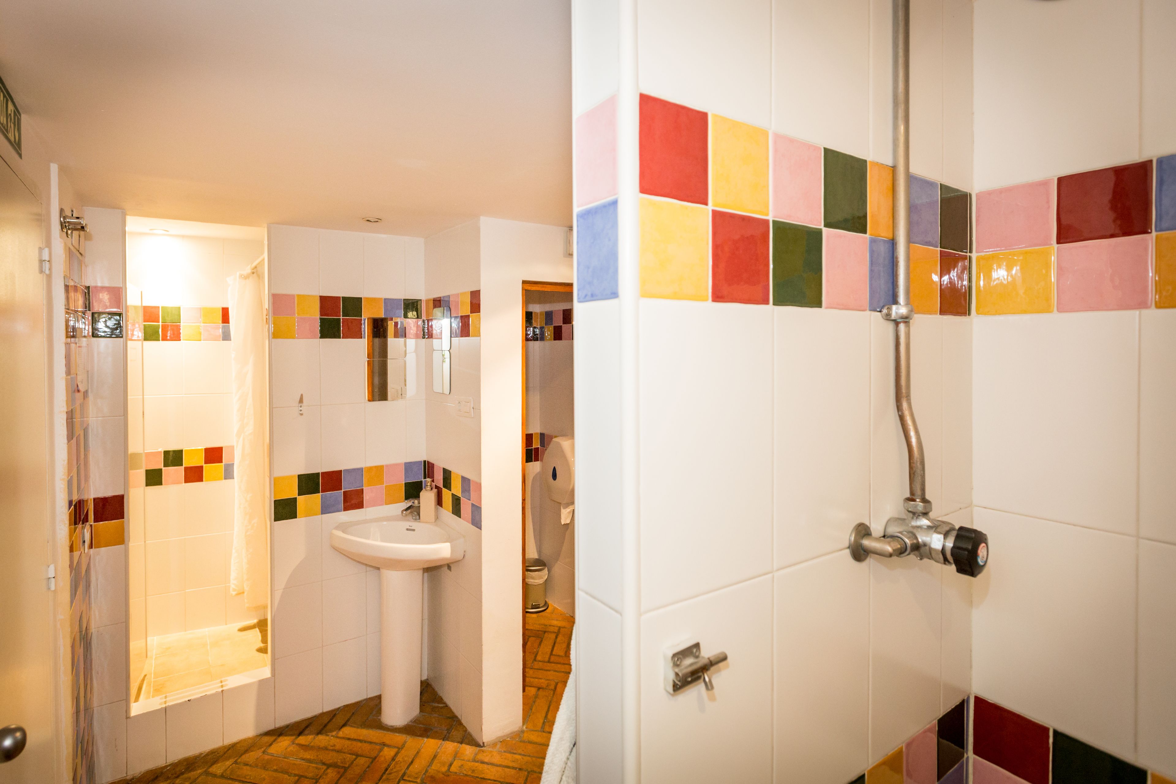 A bathroom with a tiled shower area, a sink, and a mirror.