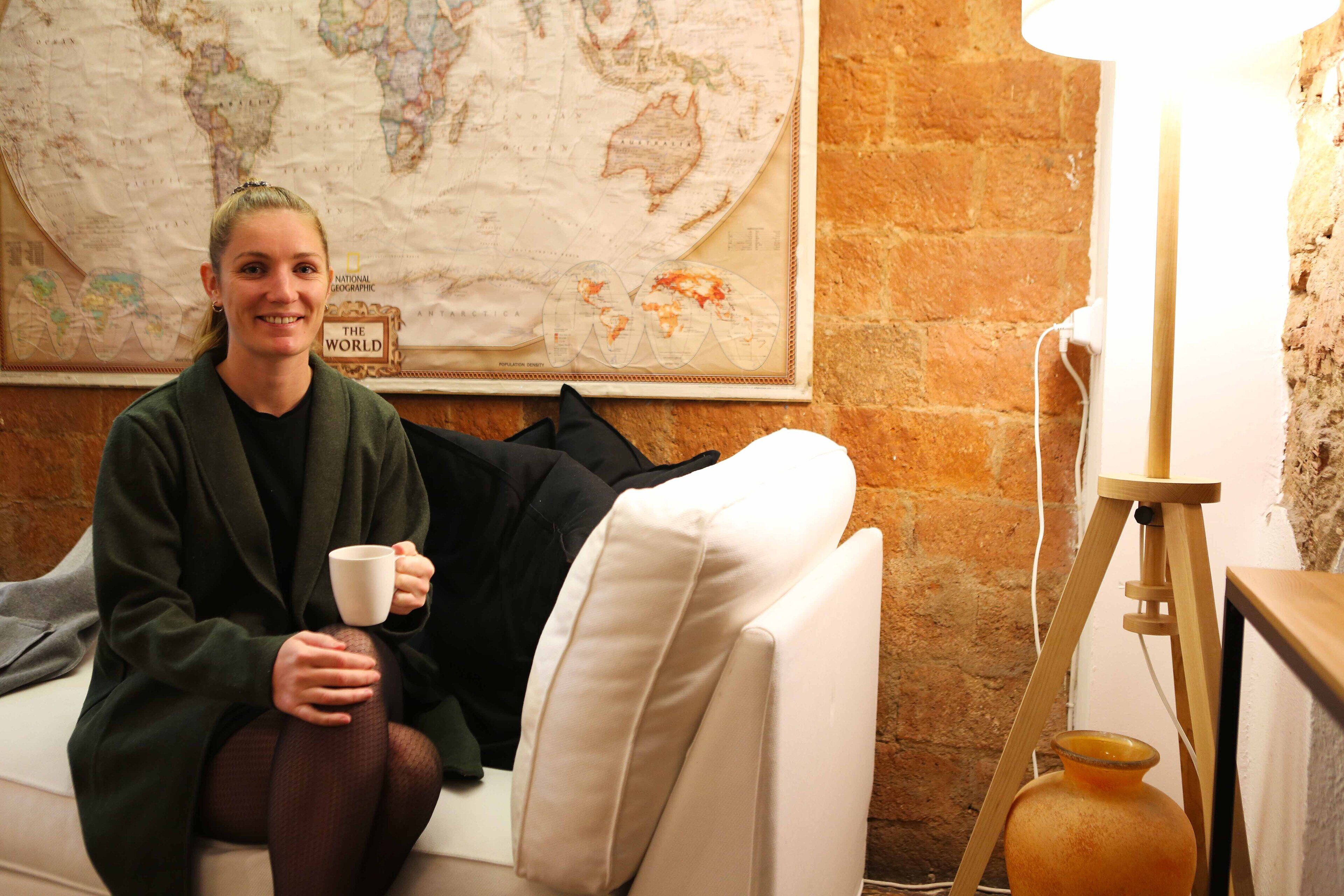 A person sitting on a white couch with a map on the wall behind them.