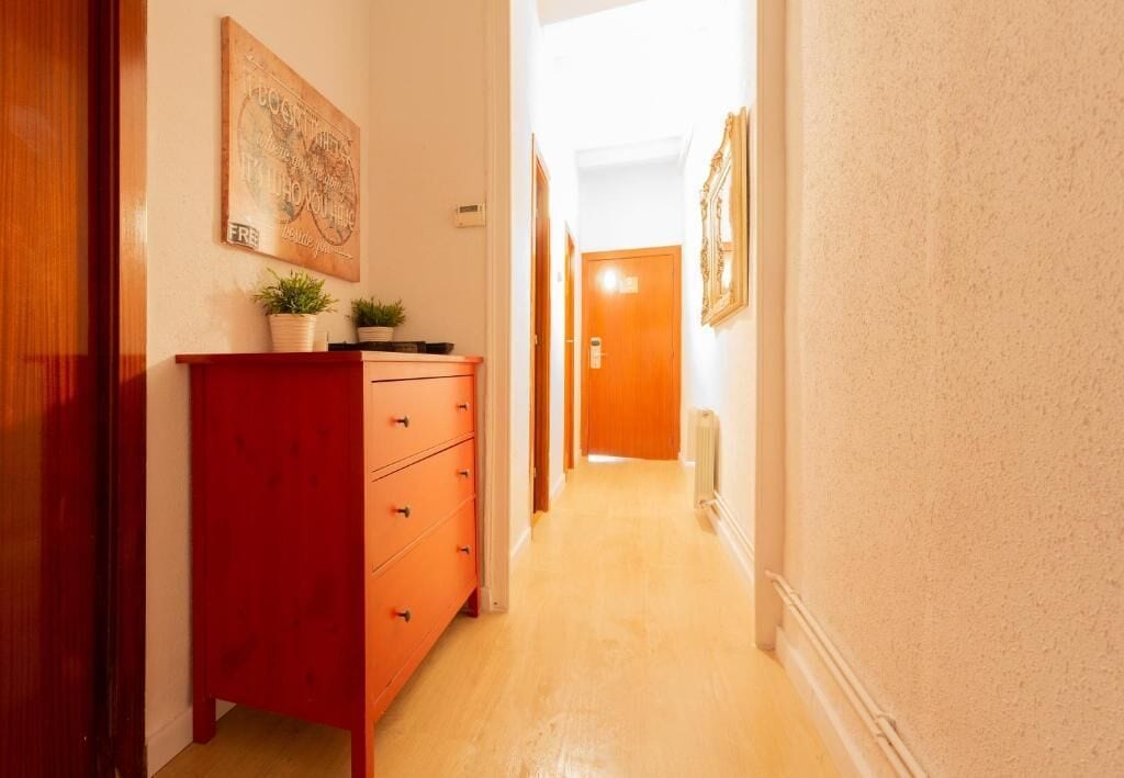 A hallway with a red dresser, a framed picture on the wall, and a door at the end.