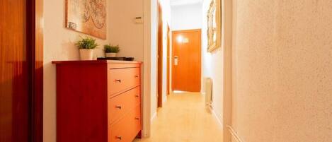 A hallway with a red dresser, a framed picture on the wall, and a door at the end.